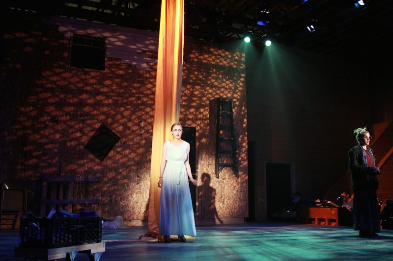 A production photo of Into the Woods. A girl stands in front of a long beautiful piece of yellow material.